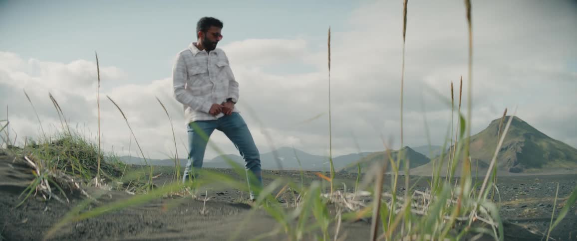 Young man energetically dancing outdoors near mountains at daytime