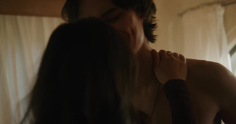 A bare chested man takes a woman by the hands and she puts her arms around his neck