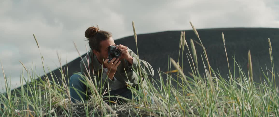 A man is taking photographs in the grass