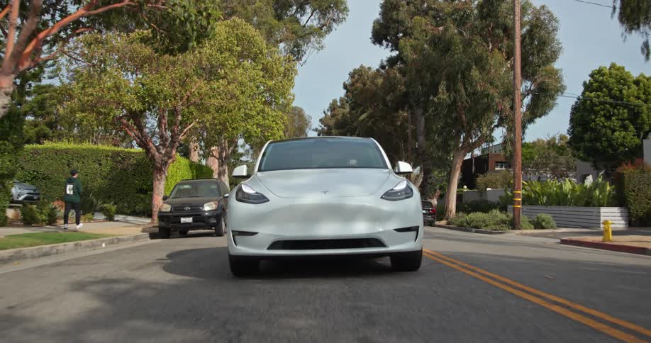 A car is driving down the road in the middle of the day