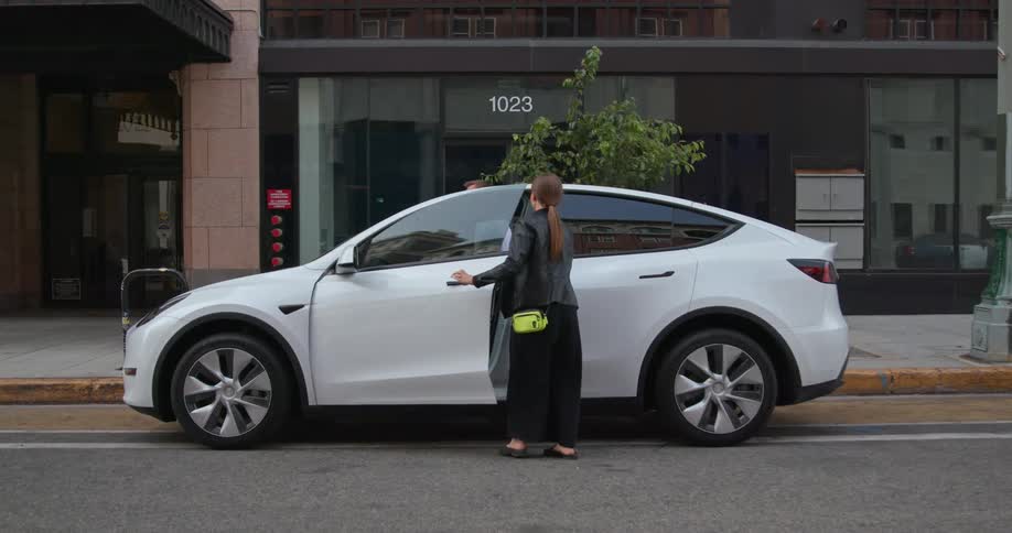 A man and a woman are walking to a car parked on a downtown street and she gets in the drivers side