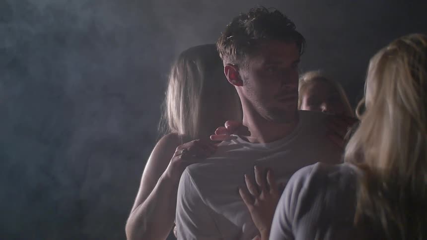 A man walks past women who are grabbing on him