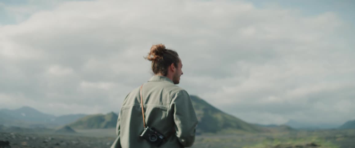 A photographer is walking through some mountains