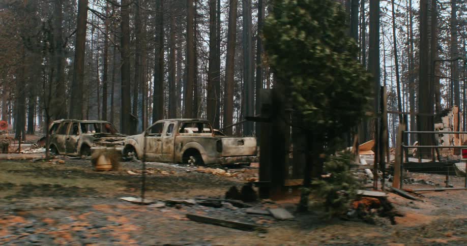 Remnants of burnt down homes and abandoned vehicles remain after a fire destroys a neighborhood