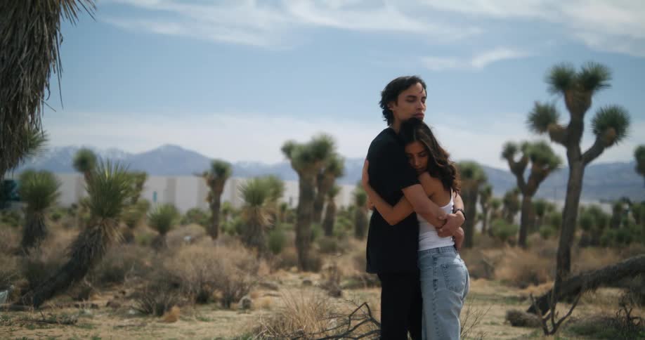 A boyfriend and girlfriend are hugging in the middle of the desert