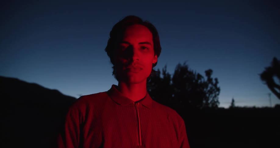 A man is standing outside in the mountains when a red light turns on to illuminate him