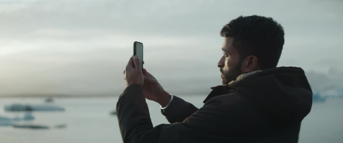 A man takes a picture of the water with his cell phone