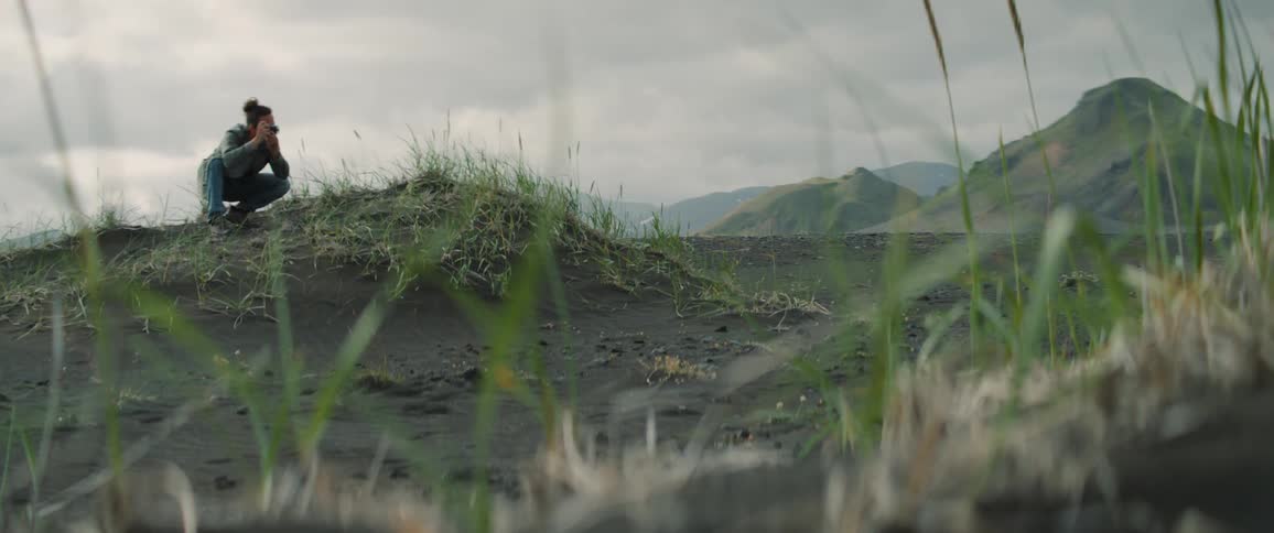 A man kneels down to take photos of rolling hills