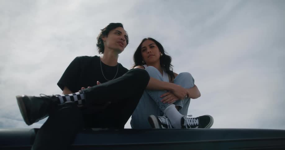 Teenagers sit and chat on top of their vehicle