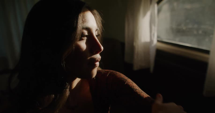 Sunlight shines on the face of a woman as she sits inside near a window
