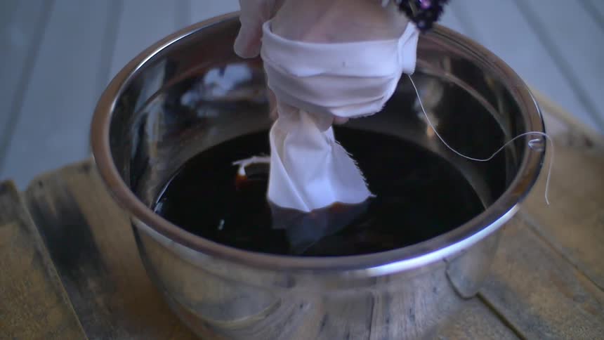 A white cloth is dipped in a bowl of dye