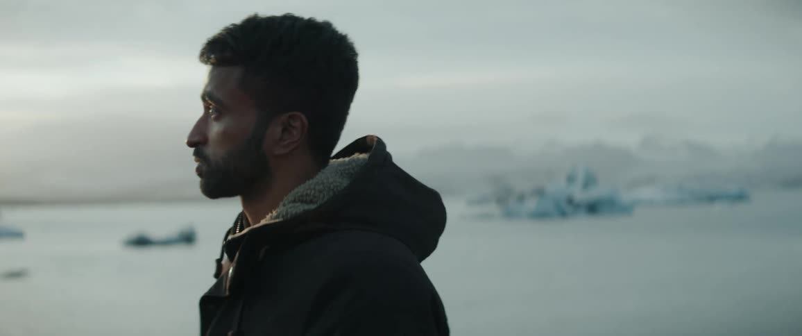 Man stands looking over ocean and sea ice before walking away