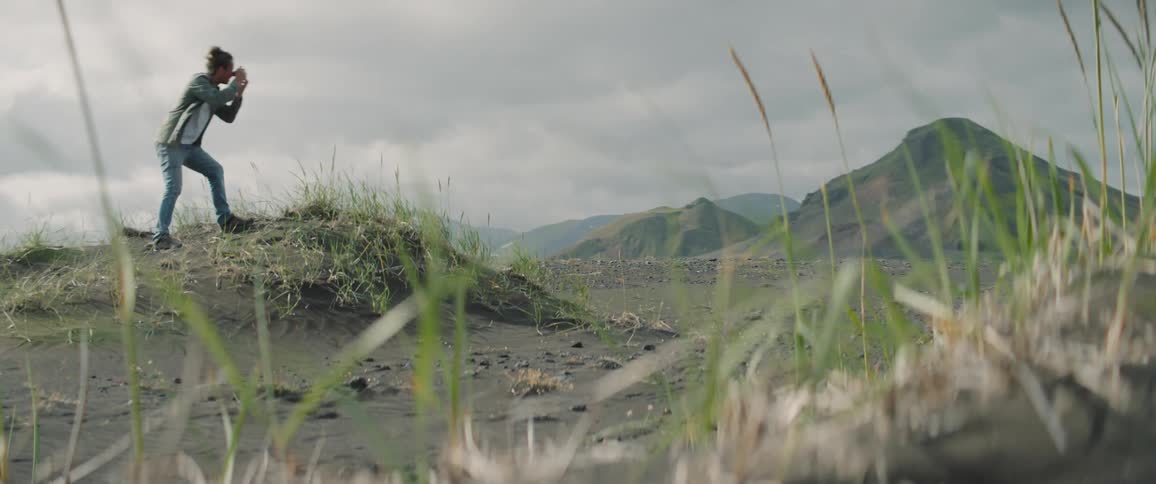 A man stands on top of a small hill to take photos