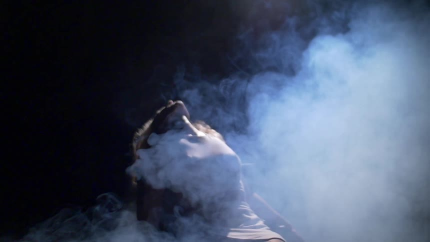 A woman is leaning back in a chair surrounded by smoke