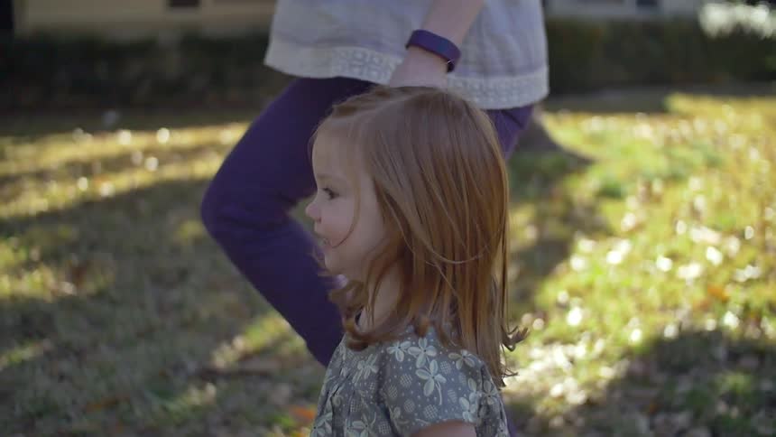 A woman walks hand in hand with a girl