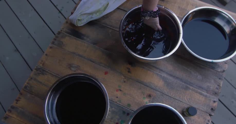 A hand is stirring one of four bowls with liquid inside