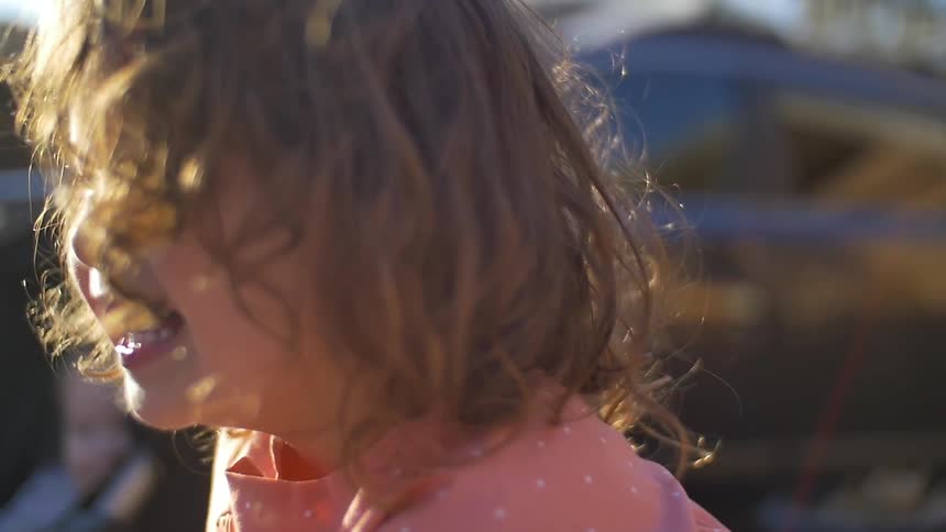 A girl looks up laughing on a sunny day