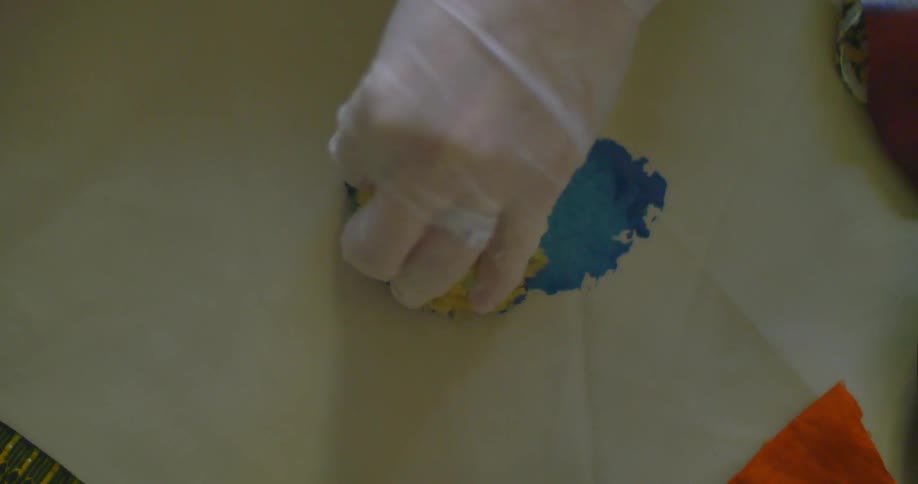 A woman dabbing a paint-soaked sponge on paper