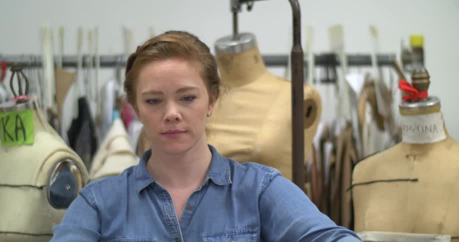 A woman unfurls a length of fabric in a workshop