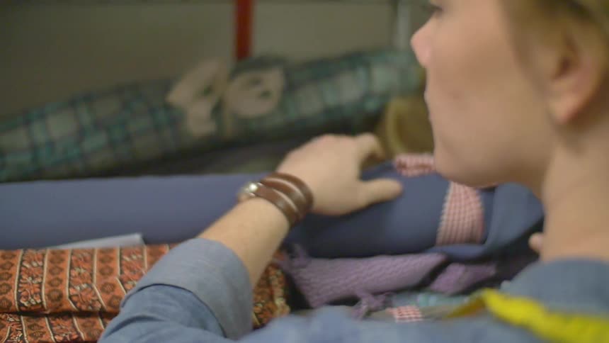 A woman searching through bolts of fabric