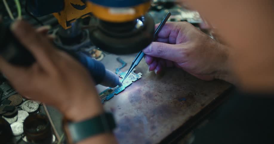 A man uses a soldering gun on a circuit board