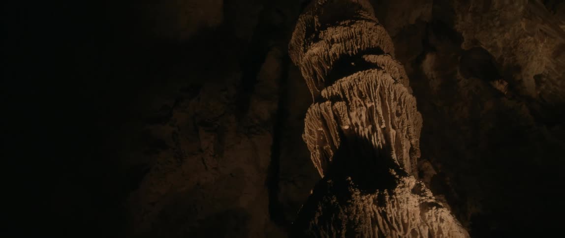 Light shines on a stalagmite rock formation inside a cave