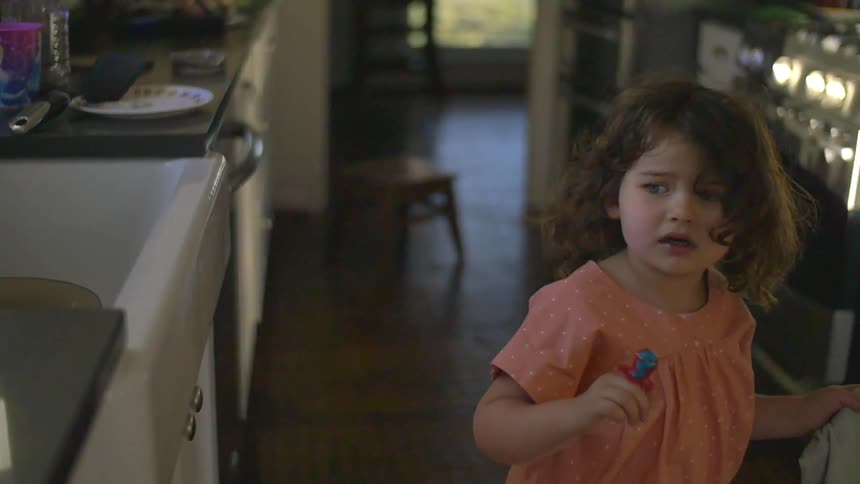 A girl is walking in the kitchen looking worried