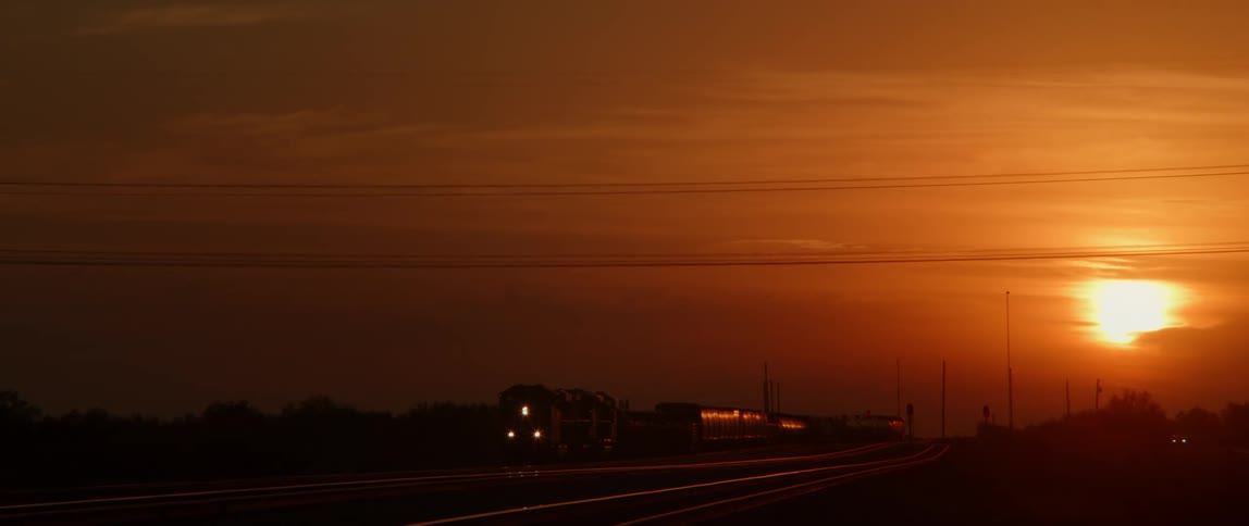 A train drives along tracks as the sun sets
