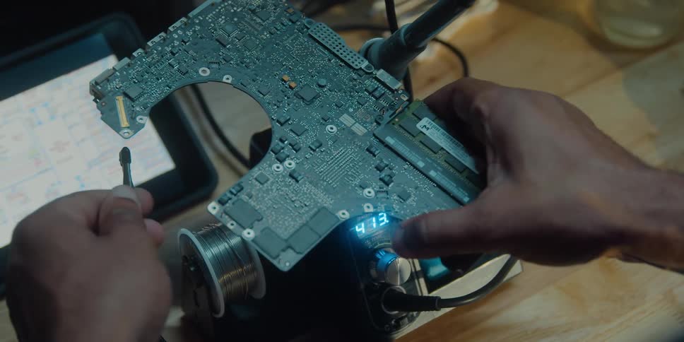 A man is working on some computer equipment and attaching a motherboard