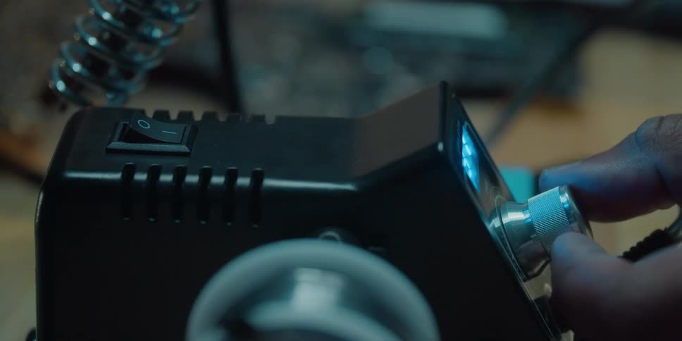 A person turning on a soldering iron
