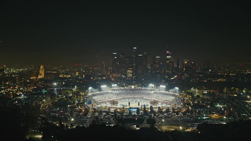 Fireworks are in the air over a city as a stadium is lit up