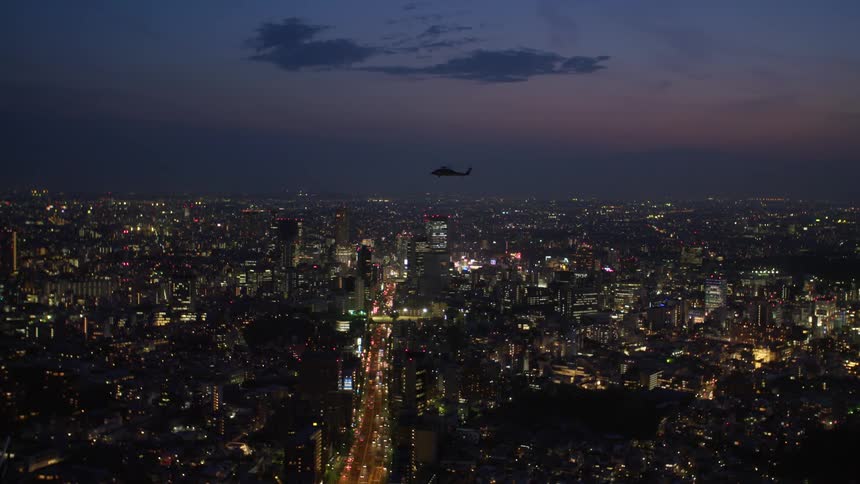 A helicopter crosses over Tokyo city at night.