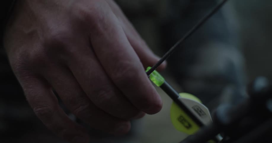 Person places arrow against string while outdoors