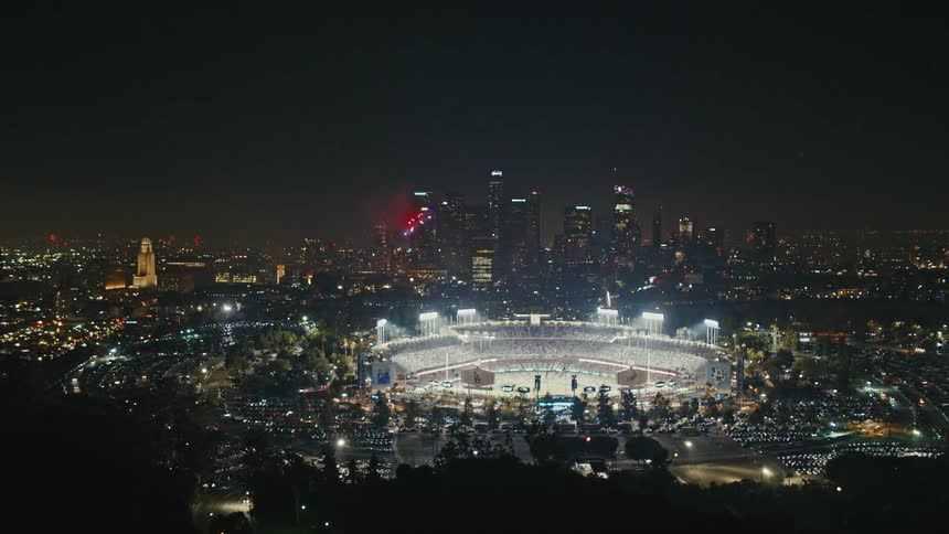 An aerial view of a city skyline with an arena and fireworks exploding in the sky