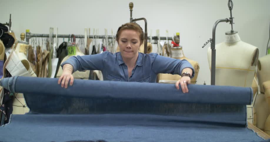 A woman rolls out a sheet of fabric