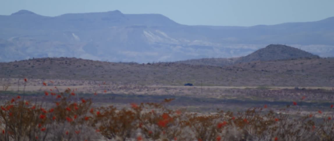 A pickup truck drives down a deserted road near mountains