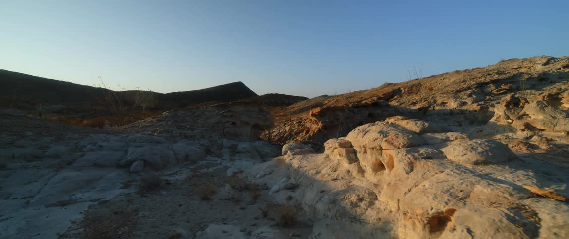 View of rocky field and hills under blue sky