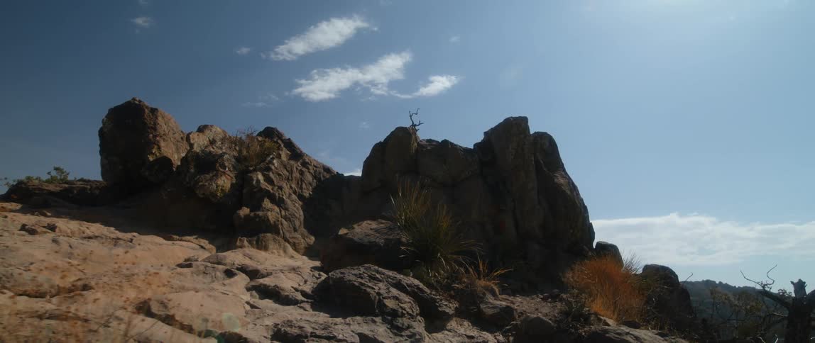 A pile of big rocks on hill under blue sky
