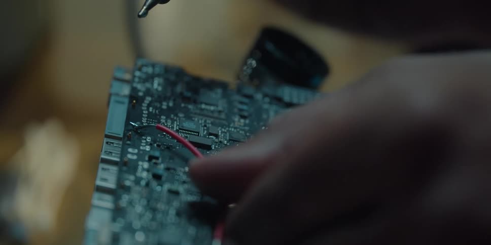 A person is soldering a wire onto a computer board
