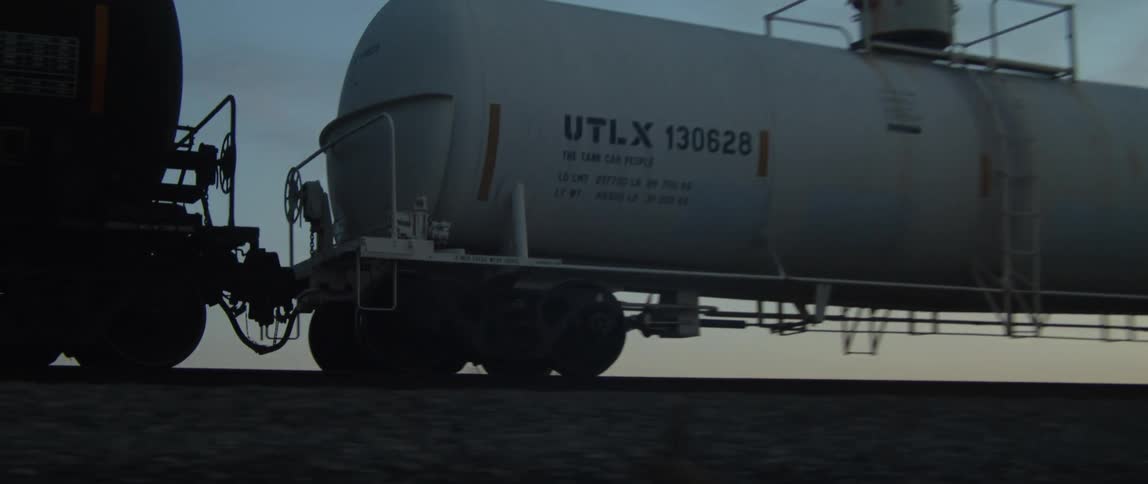 A freight train traveling through a rural area at sunrise