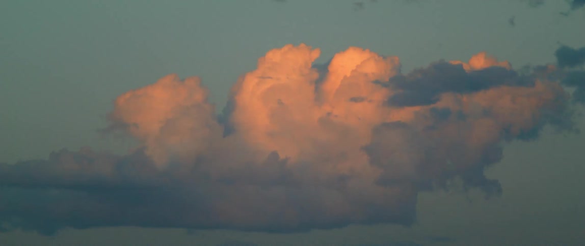 Sunlight illuminates the top of a cloud at sunset