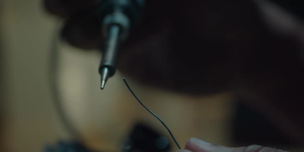 Smoke curls up from the tip of a soldering iron on wire