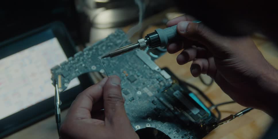 A man is working on the wires of a motherboard