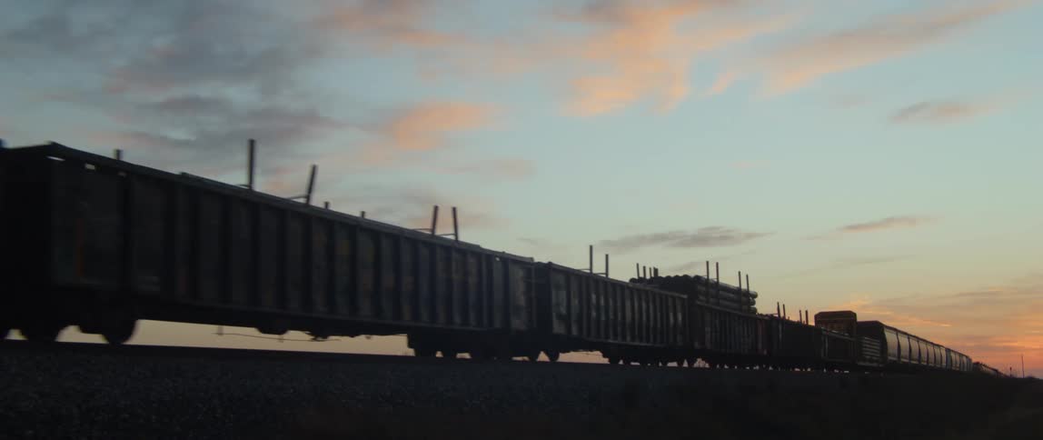 Train party silhouetted against the red tinted horizon move along track