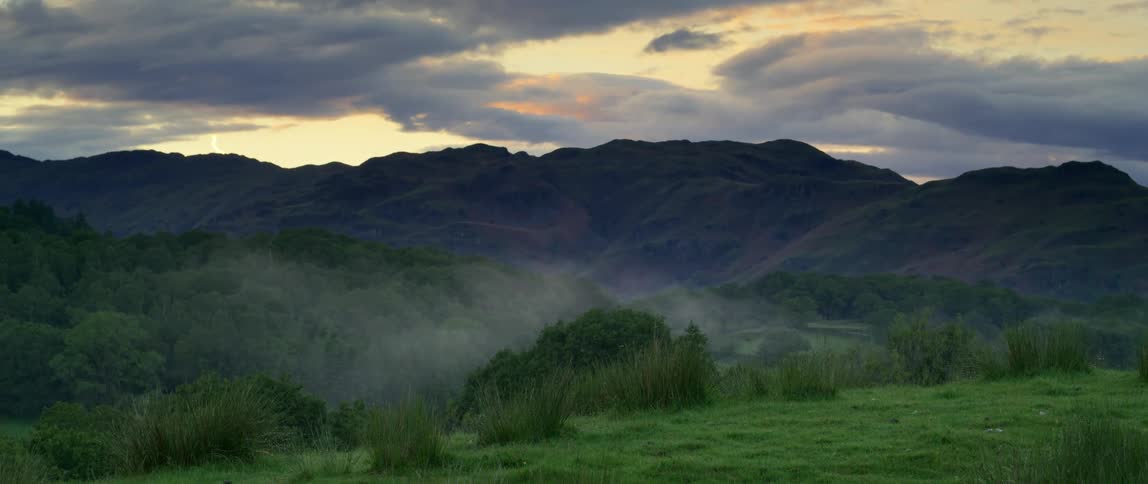 A haze over top of a grassy field with hills in the distance