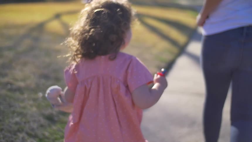 A girl runs alongside a woman on the sidewalk