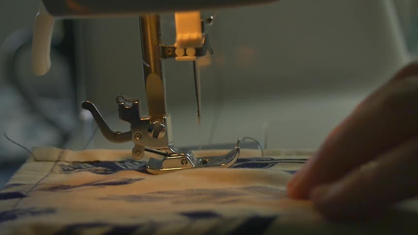 A sewing machine has fabric fed past it's needle