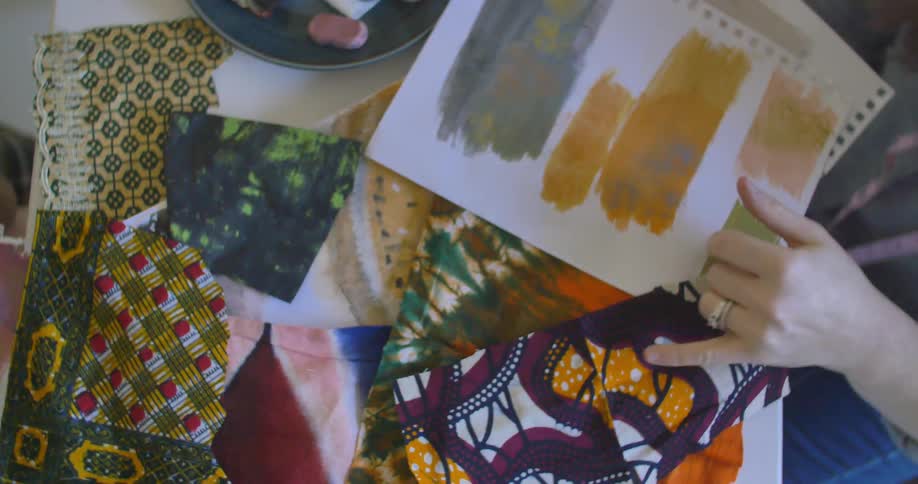 People examine pieces of fabric and paper on a table