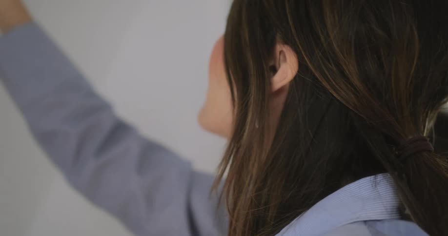A woman is putting art up on a wall
