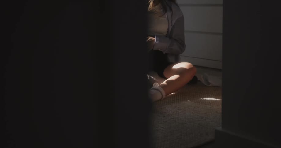 Expectant mother rubs belly as she sits on floor examining paper